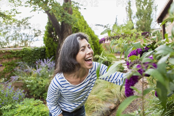 Hispanic woman looking at flowers in garden