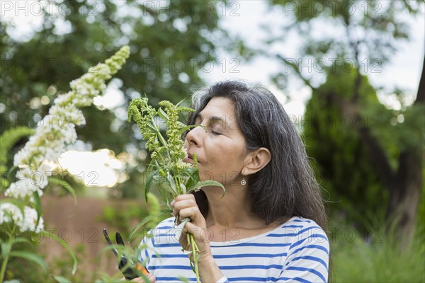 Hispanic woman smelling flowers in garden