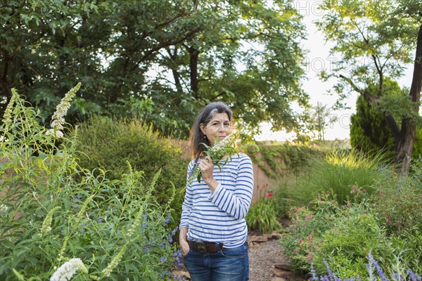 Hispanic woman smelling flowers in garden