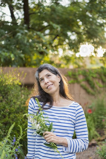 Hispanic woman holding flowers in garden
