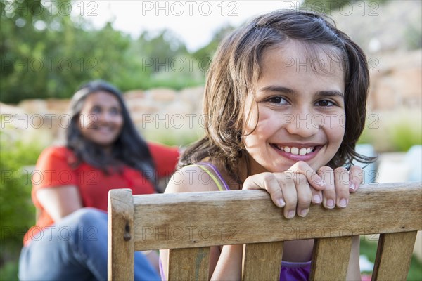 Girl smiling in wooden chair outdoors