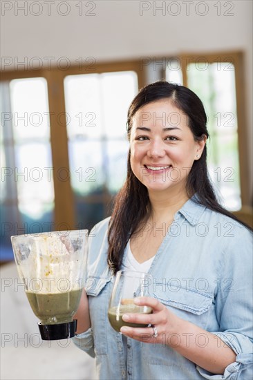 Mixed race woman drinking green smoothie