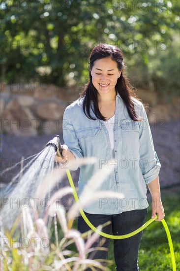 Mixed race woman watering plants in garden