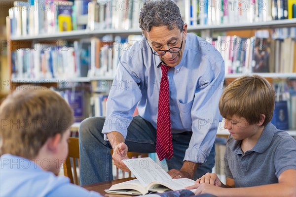 Teacher and students working in library