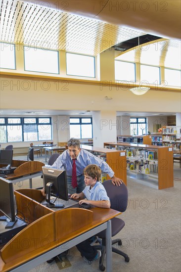 Teacher and student working at computer in library