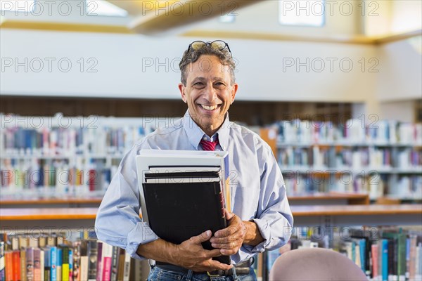 Senior man holding books in library