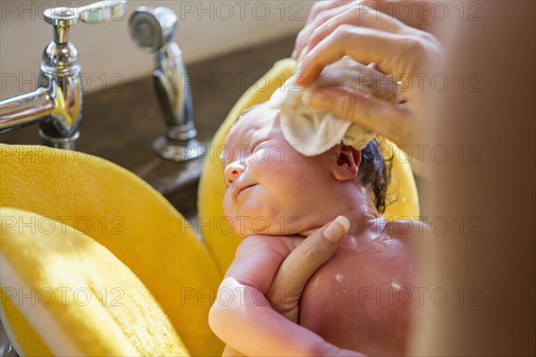 Caucasian newborn baby boy having bath