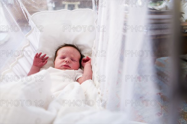 Caucasian newborn baby boy laying in crib