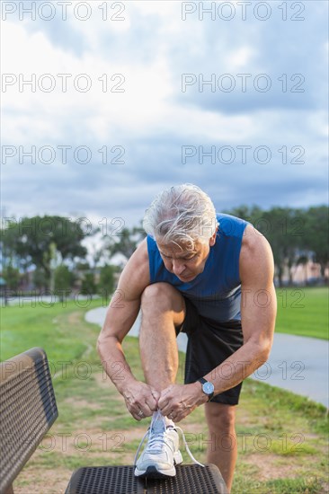 Hispanic man tying shoe in park