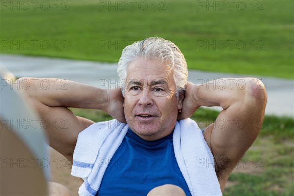Hispanic man doing sit-ups in park