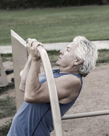 Hispanic man doing pull-ups in park