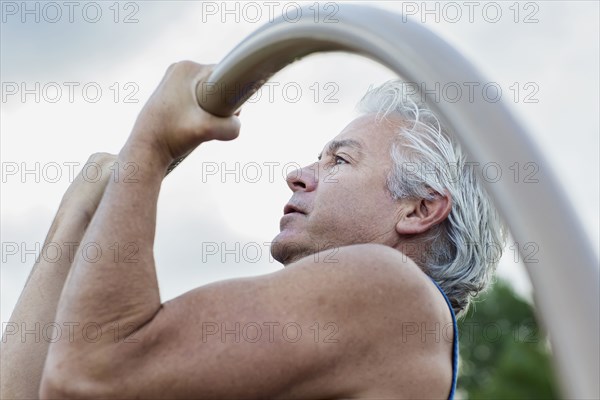 Hispanic man doing pull-ups outdoors