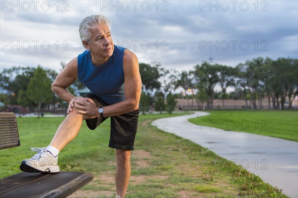 Hispanic man stretching in park