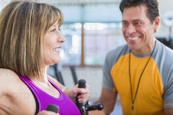 Caucasian woman working with personal trainer in gym