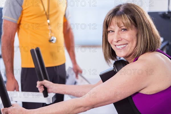 Caucasian woman working with personal trainer in gym