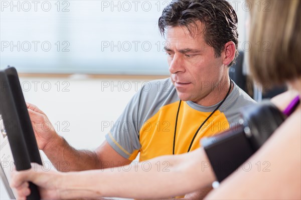 Caucasian woman working with personal trainer in gym