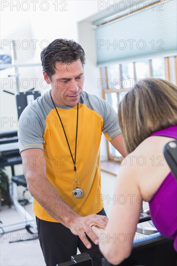 Caucasian woman working with personal trainer in gym