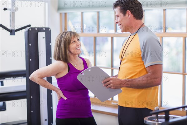 Caucasian woman working with personal trainer in gym