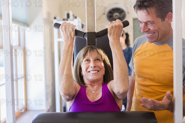 Caucasian woman working with personal trainer in gym