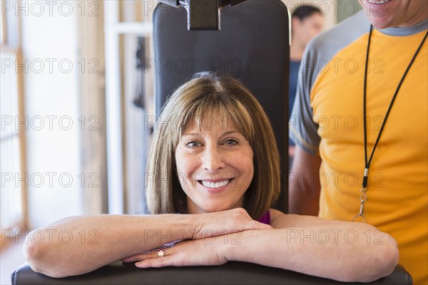 Caucasian woman working with personal trainer in gym