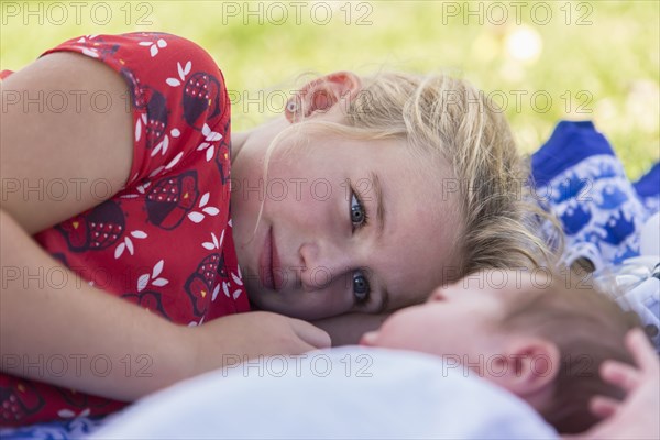 Caucasian girl laying with newborn baby brother