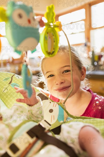 Caucasian girl playing with newborn baby brother