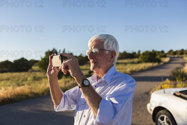 Senior Caucasian man taking pictures with cell phone