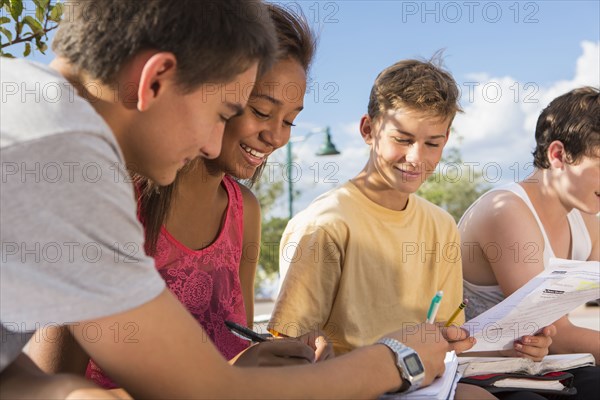 Teenagers doing homework together outdoors