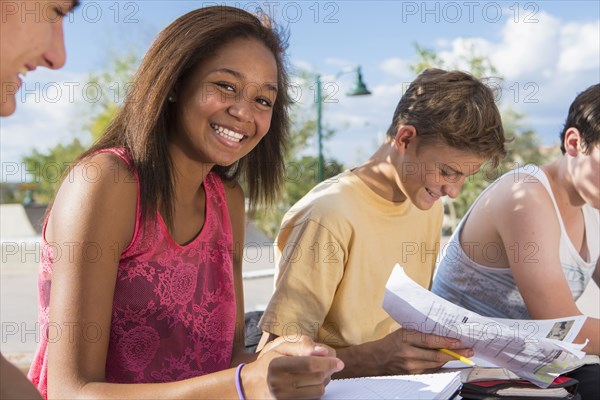 Teenagers doing homework together outdoors