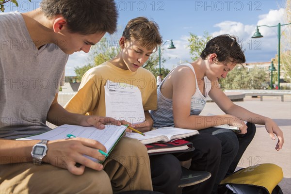 Teenage boys doing homework together outdoors