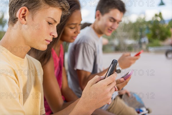 Teenagers using cell phones outdoors