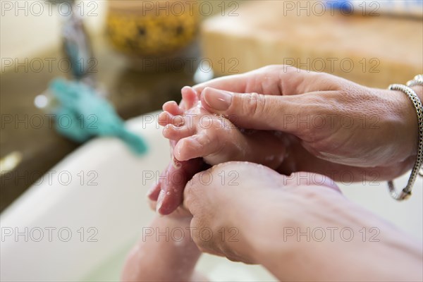 Caucasian mother washing newborn's foot