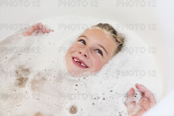 Caucasian girl laying in bubble bath