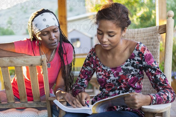 Mother helping daughter with homework on patio