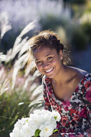 Mixed race teenage girl smiling outdoors with bouquet