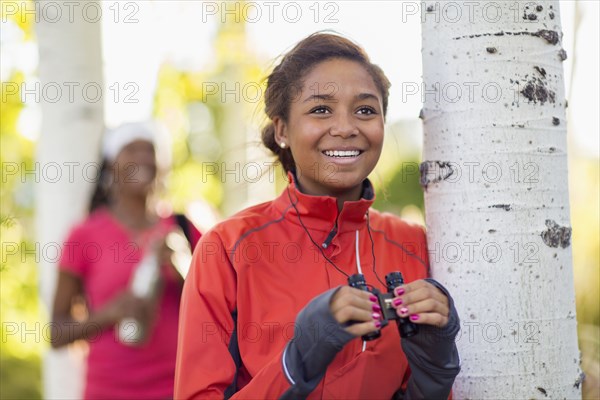 Mixed race teenage girl using binoculars outdoors