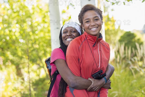 Mother hugging daughter in woods