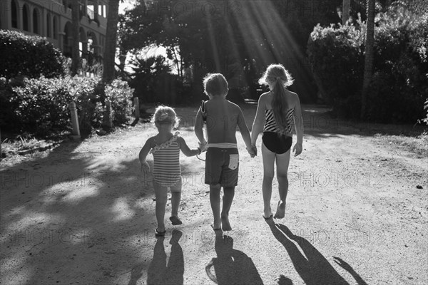 Children in swimsuits holding hands outdoors