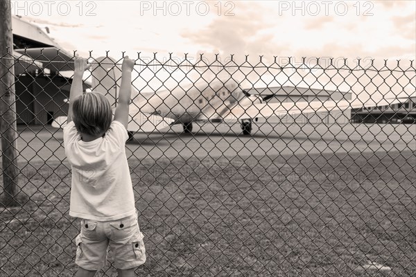 Boy climbing chain link fence around airport