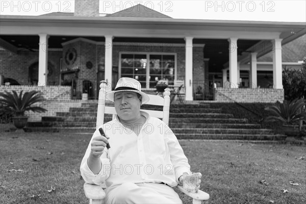 Caucasian man relaxing with cigar in yard