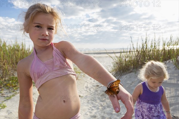 Caucasian girl holding butterfly on beach