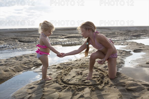 Caucasian sisters playing together on beach