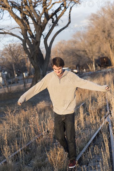 Mixed race teenage boy walking on train tracks