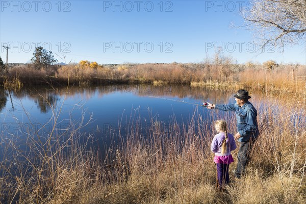 Senior man and granddaughter watching calm lake