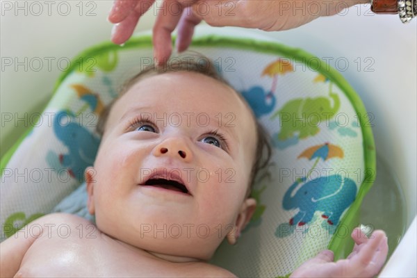 Caucasian mother bathing baby in tub