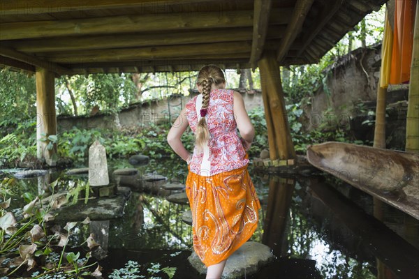 Caucasian girl walking on rocks in pond