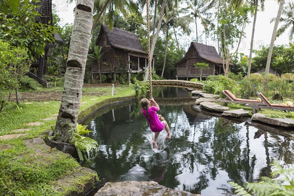 Caucasian girl swinging on rope in garden