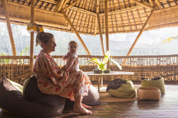 Caucasian mother bouncing baby on knee