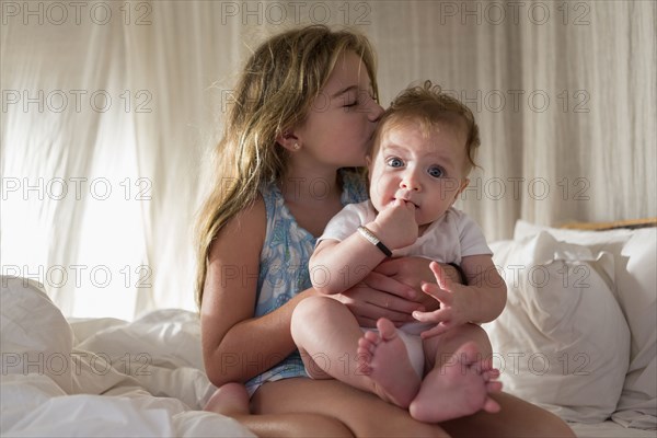 Caucasian girl kissing sibling on sofa