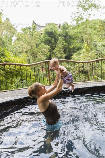 Caucasian mother and baby playing in pool